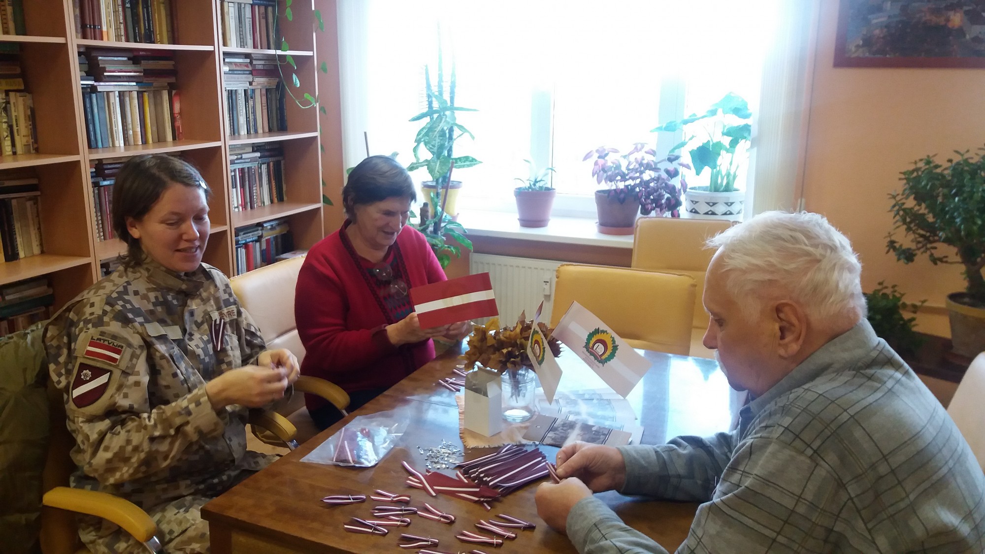 Seniori piedalās sarkanbaltsarkano lentīšu locīšanas akcijā