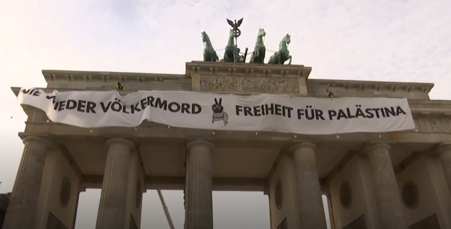 Pie Berlīnes Brandenburgas vārtiem izkārts plakāts palestīniešu atbalstam